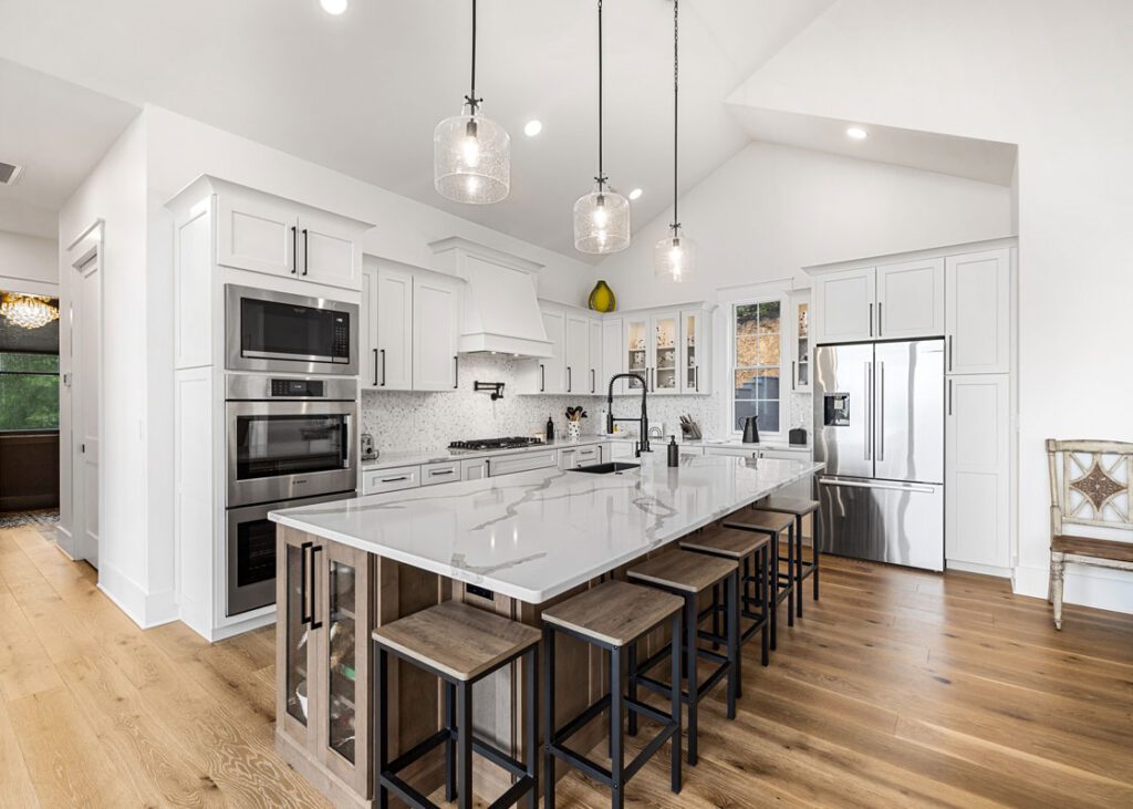 Bright modern kitchen with white cabinets, a large island, pendant lighting, and stainless steel appliances