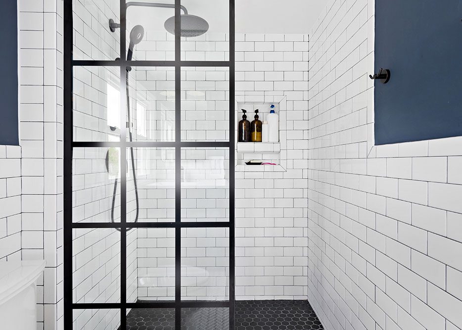 Modern walk-in shower with white subway tile and black grid glass door