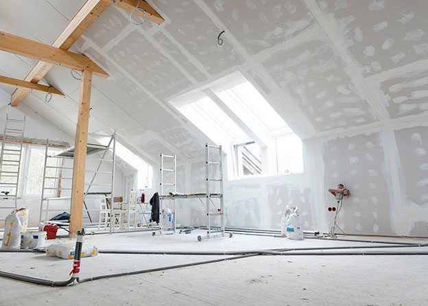 Home renovation in progress with drywall installation and exposed beams