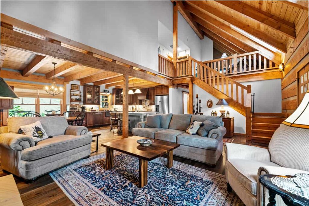 Spacious living room in a log cabin with wooden beams, sofas, and a coffee table.