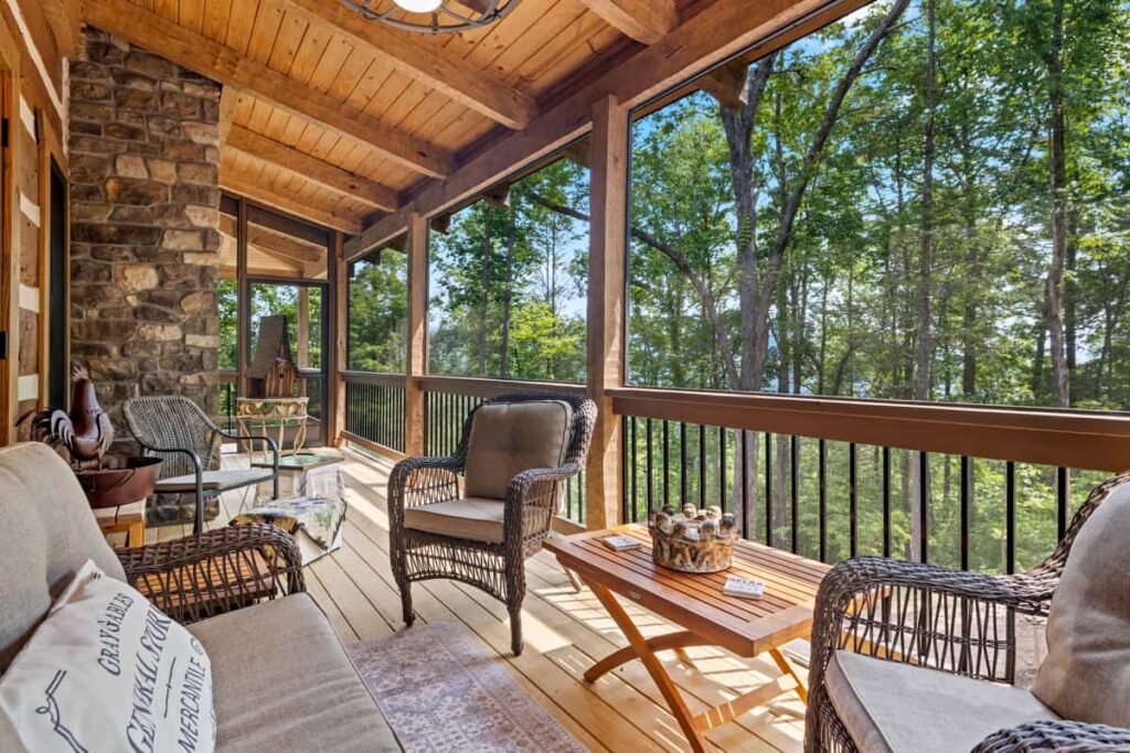 A log cabin porch surrounded by tall trees and a peaceful forest setting.