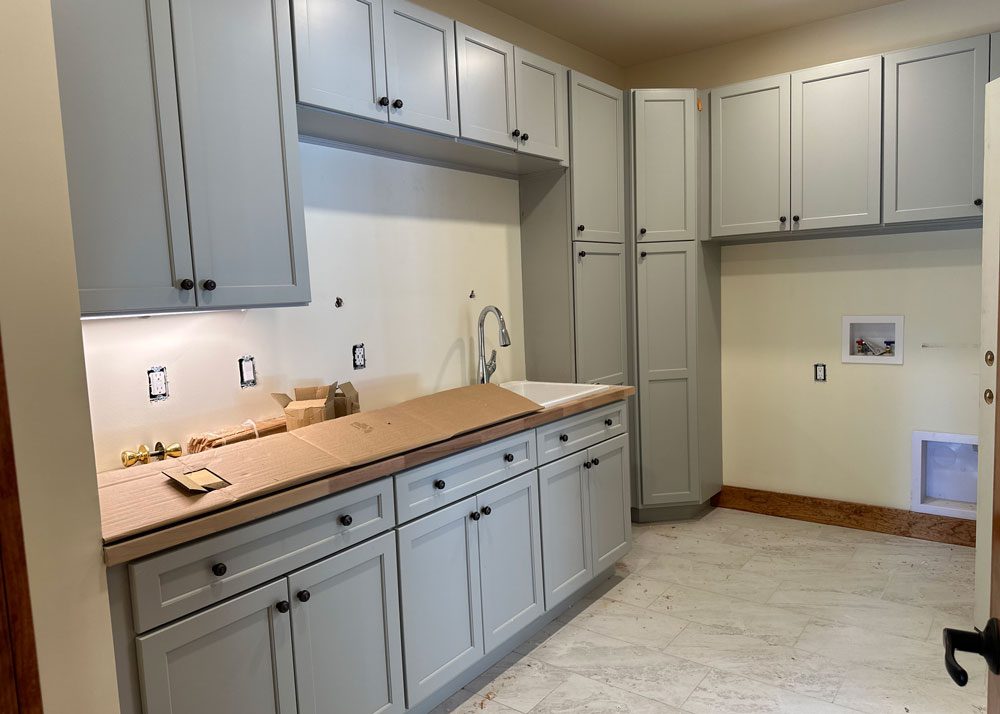 Kitchen remodel featuring white cabinets, a gray tile backsplash, pendant lighting, and stainless steel appliances