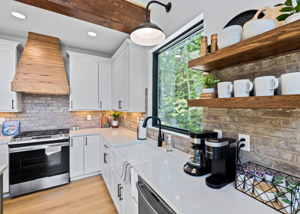 Rustic modern kitchen remodel with white cabinets, wood shelving, a brick backsplash, and large window lighting