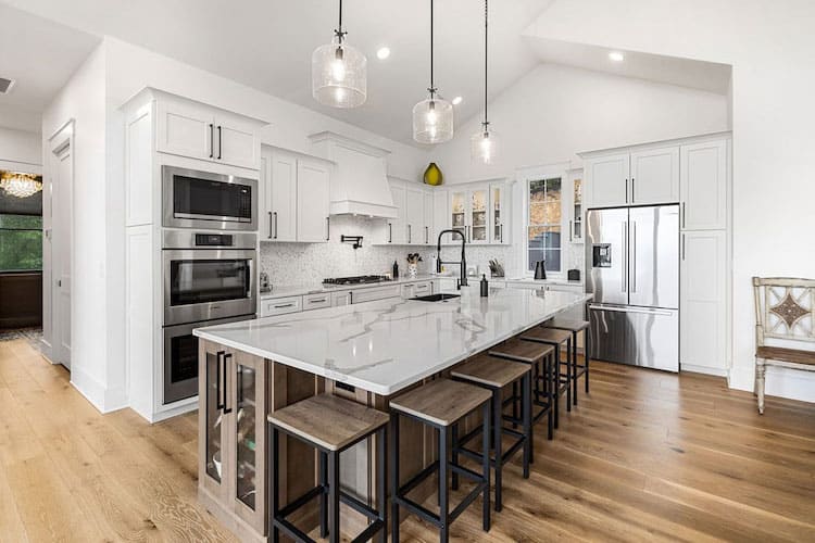 Bright modern kitchen with white cabinets, a large island, pendant lighting, and stainless steel appliances