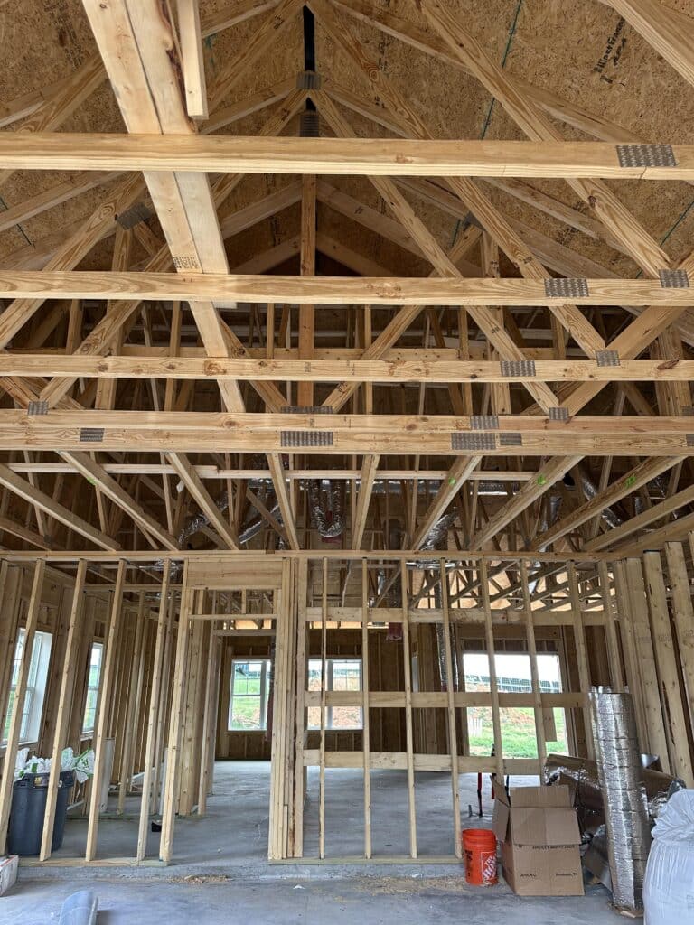 Interior framing of a large open living area with vaulted ceiling trusses and HVAC ductwork rough-in on a new construction home in Maryville Tennessee